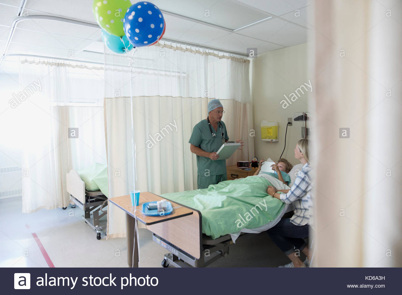 Male Surgeon Doctor Talking To Mother And Son Boy Patient In Hospital