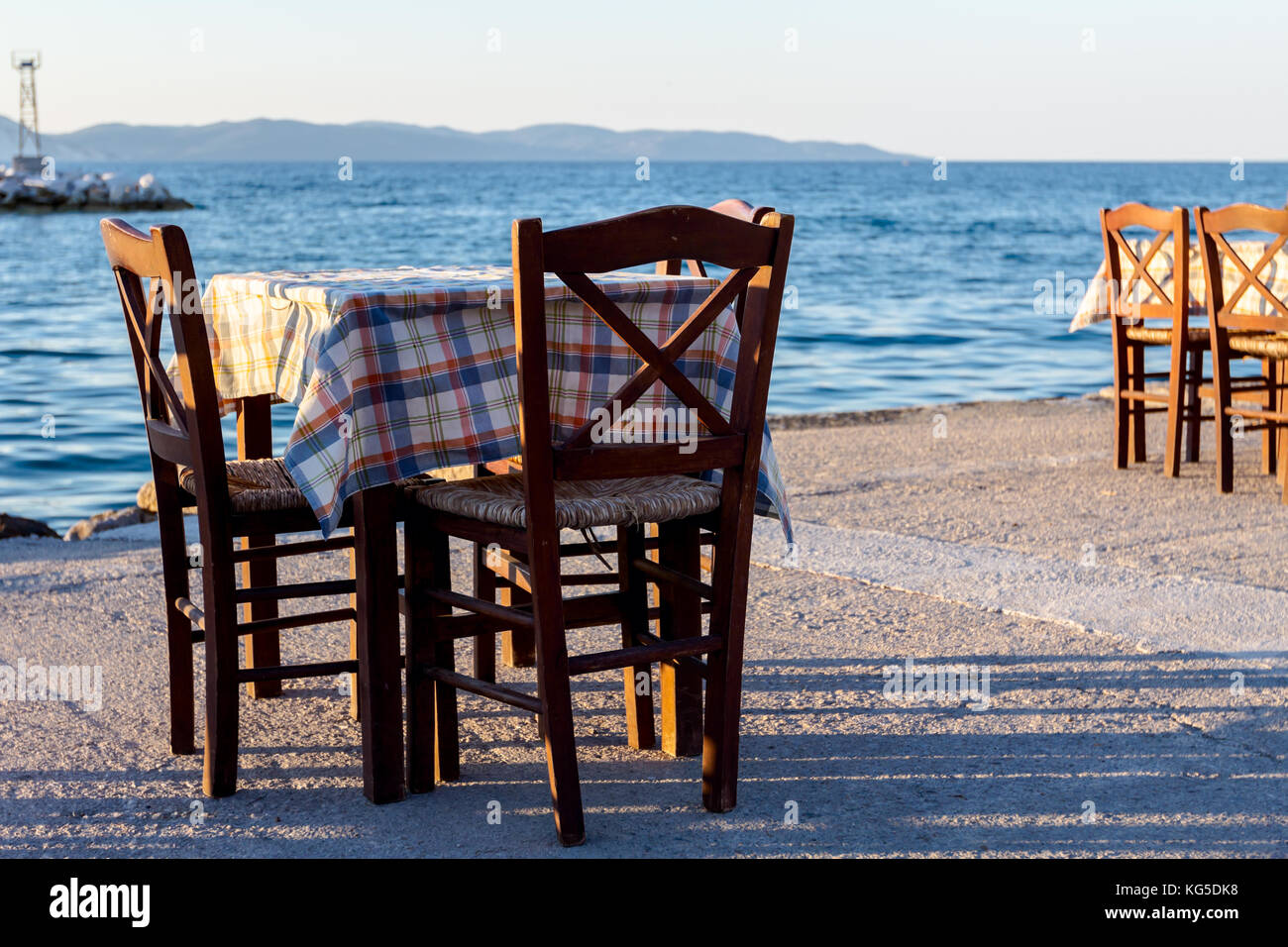 Chairs And Tables In Typical Outdoor Greek Tavern In Sunset Light With