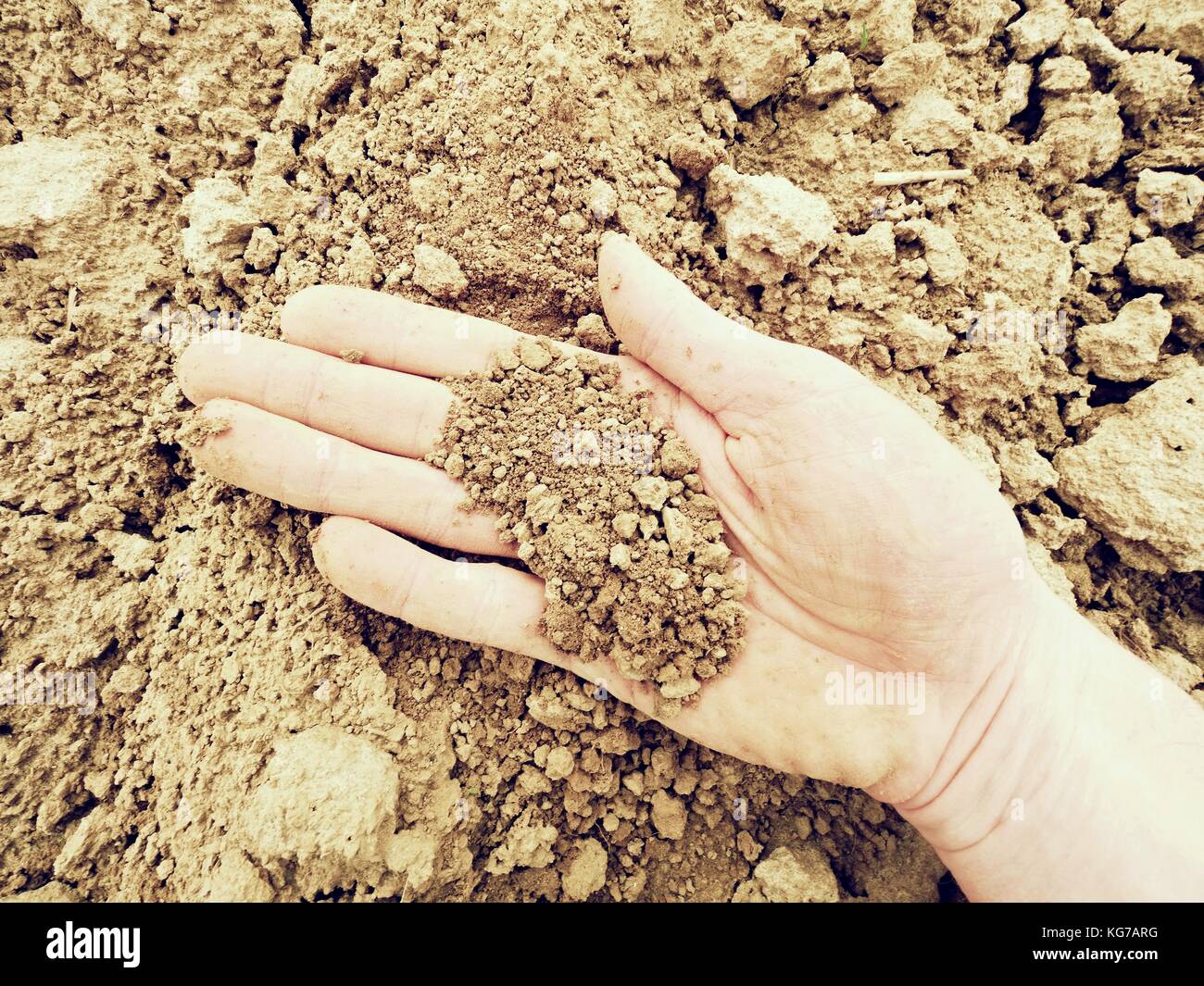 pink skin hand looking for something in wet brown clay in the field