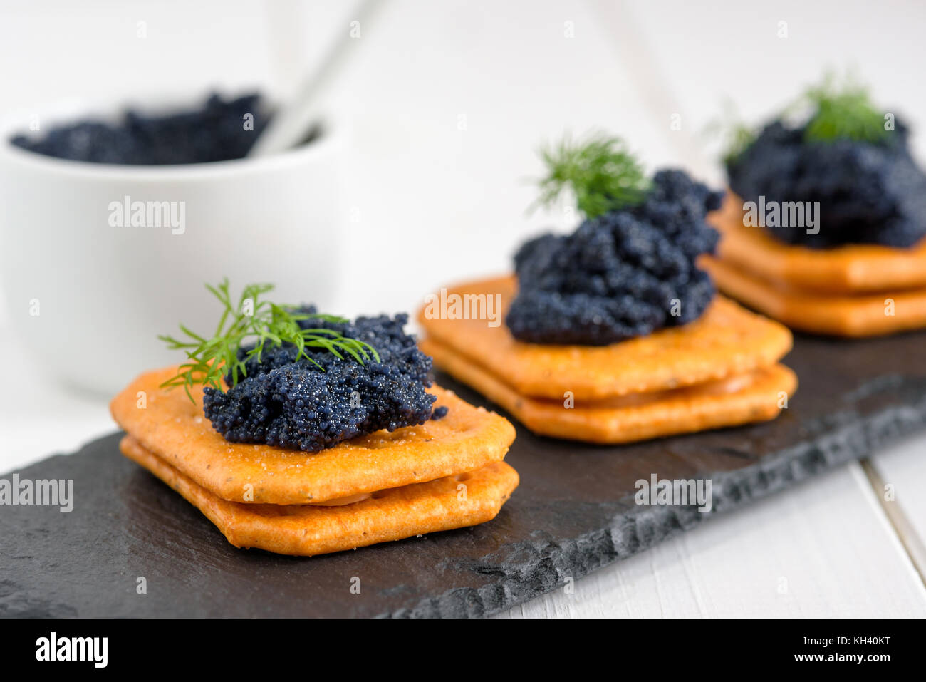 Appetizer crackers with black caviar decorated by dill Stock Photo