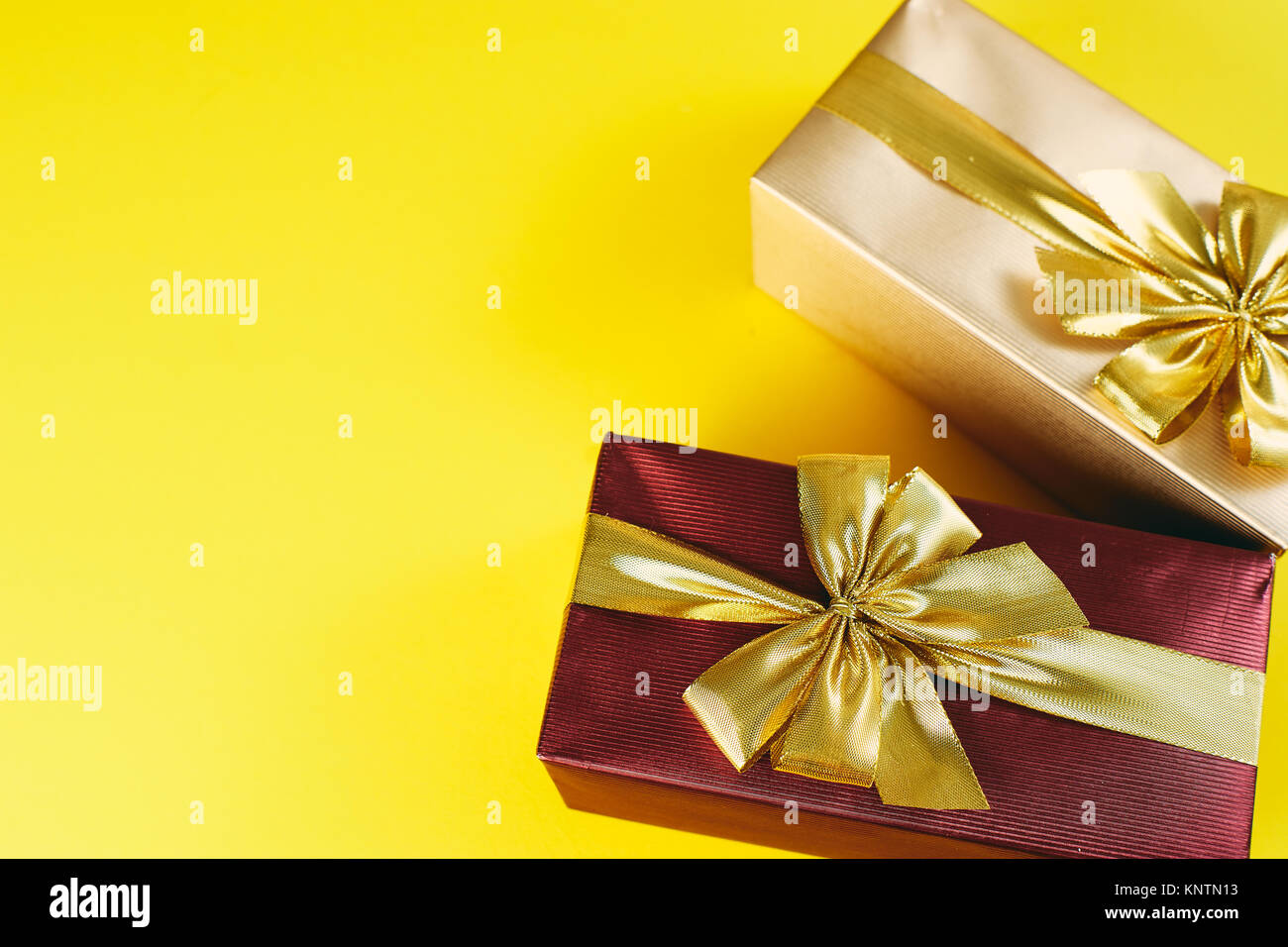 gift boxes with big golden bow knots on yellow background copy