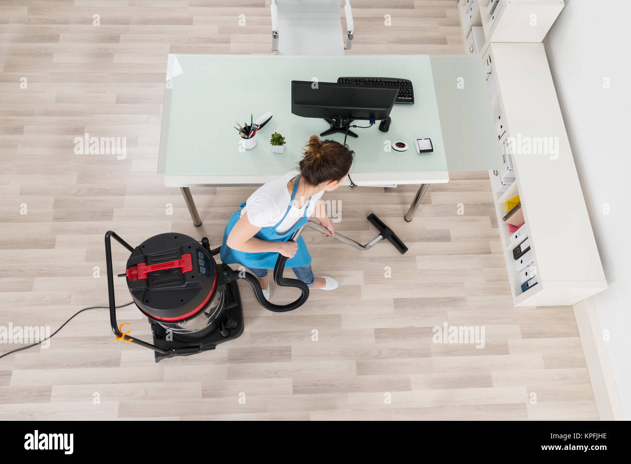 Female Janitor Cleaning Wooden Floor With Vacuum Cleaner Stock Photo