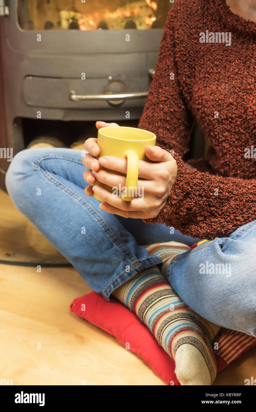 Woman Sitting With Tea Mug In Front Of Burning Stoves Stock Photo Alamy