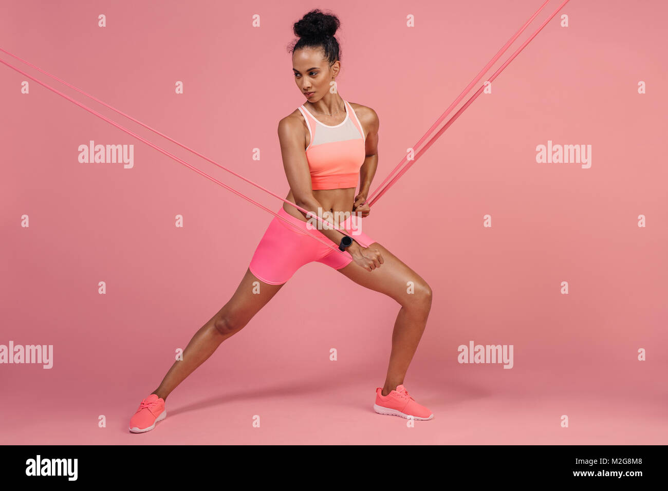 Female Athlete Stretching Resistance Band On Pink Background Sports