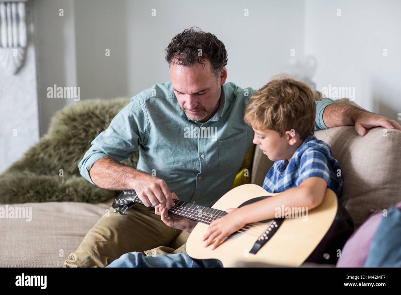 father teaching son guitar