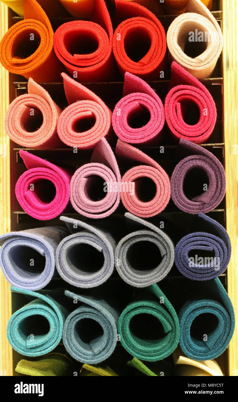 many colored big rolls of fabric in the rack of the tailoring for