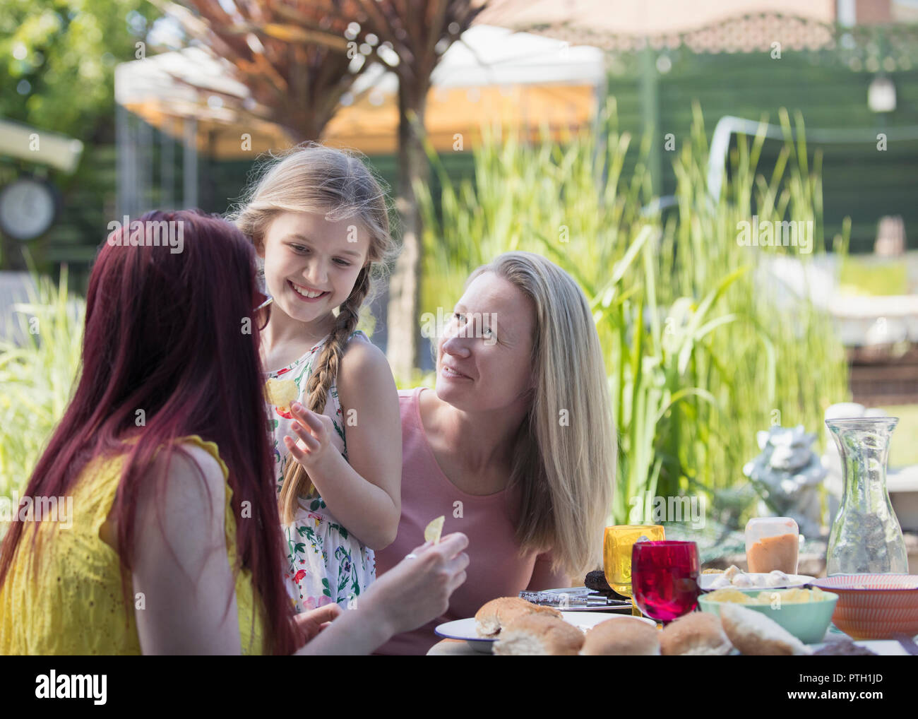 Affectionate Lesbian Couple And Daughter Enjoying Lunch On Patio Stock