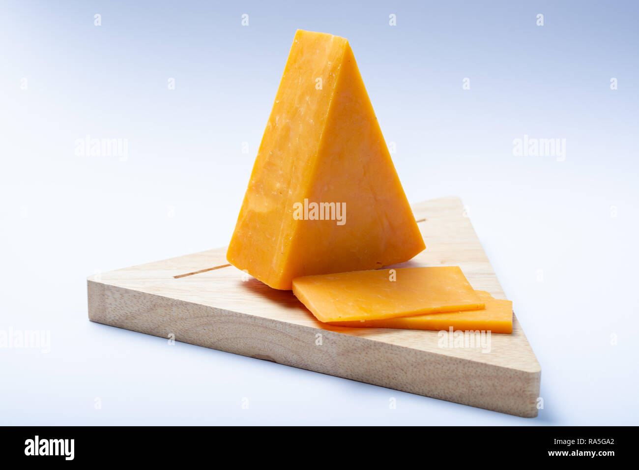 Piece Of Hard Orange Cheddar Cheese On Wooden Cheese Plank Isolated