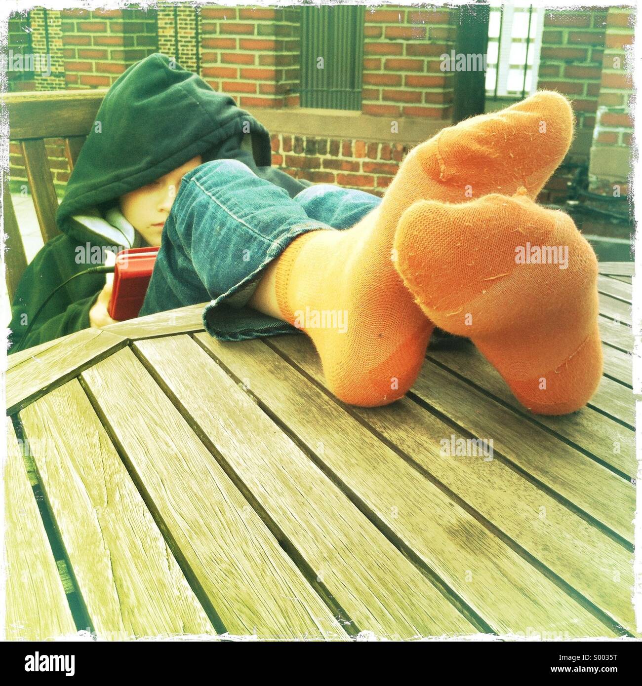 A young boy sitting at a table with his feet up Stock Photo, Royalty