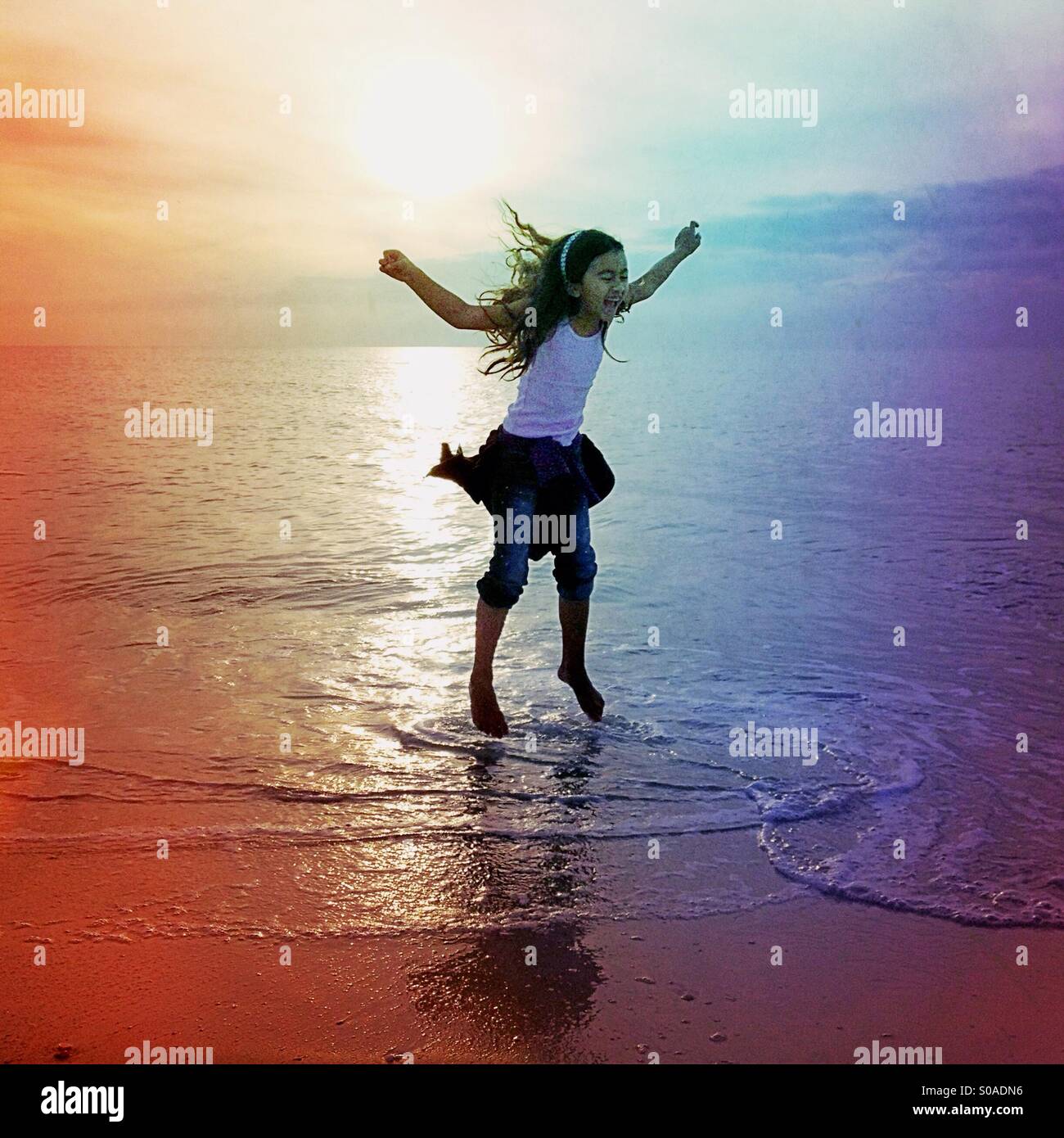 Little girl jumping upanddown in the water on the beach Stock Photo
