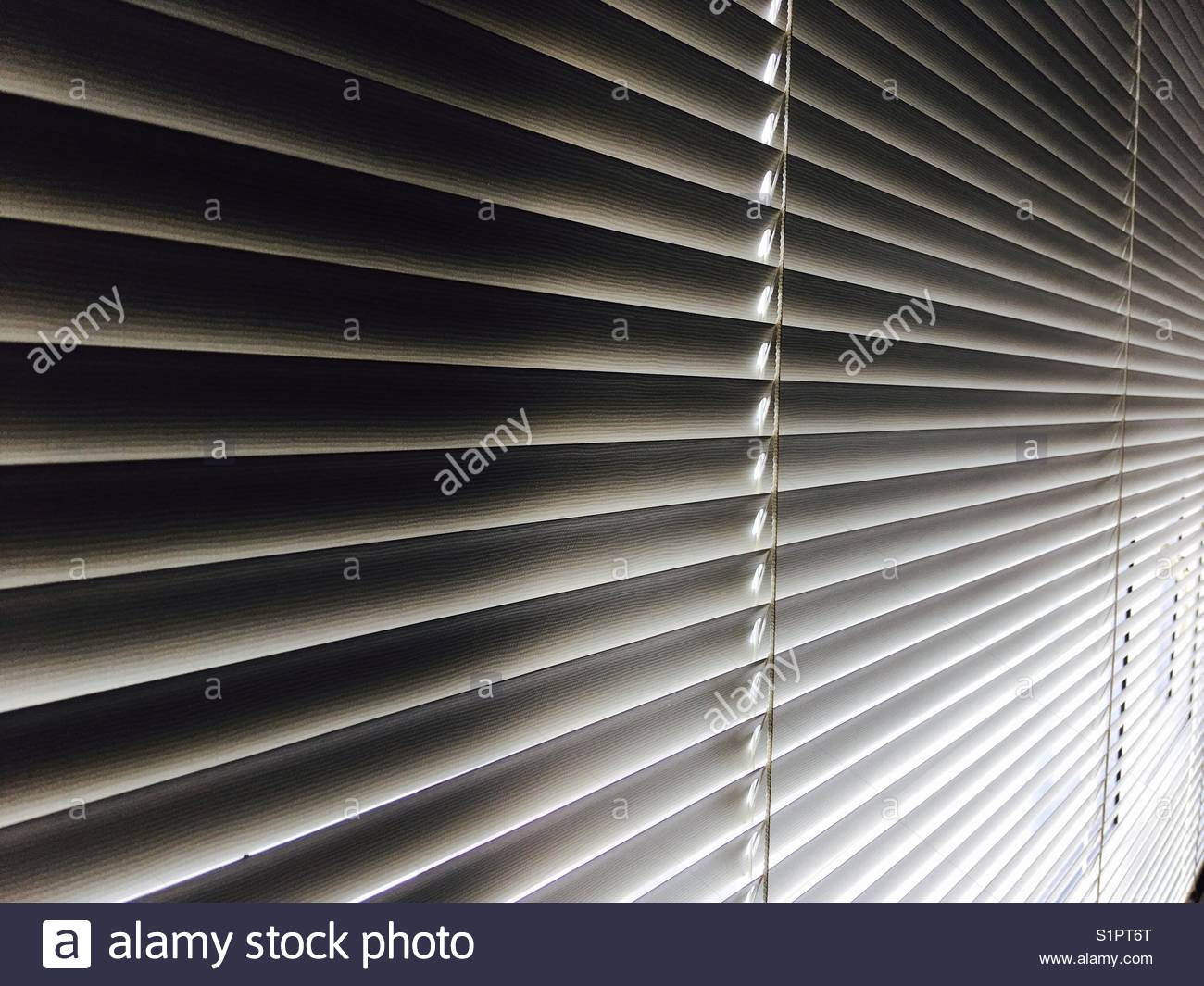 Closed window blind with light peeking through Stock Photo, Royalty