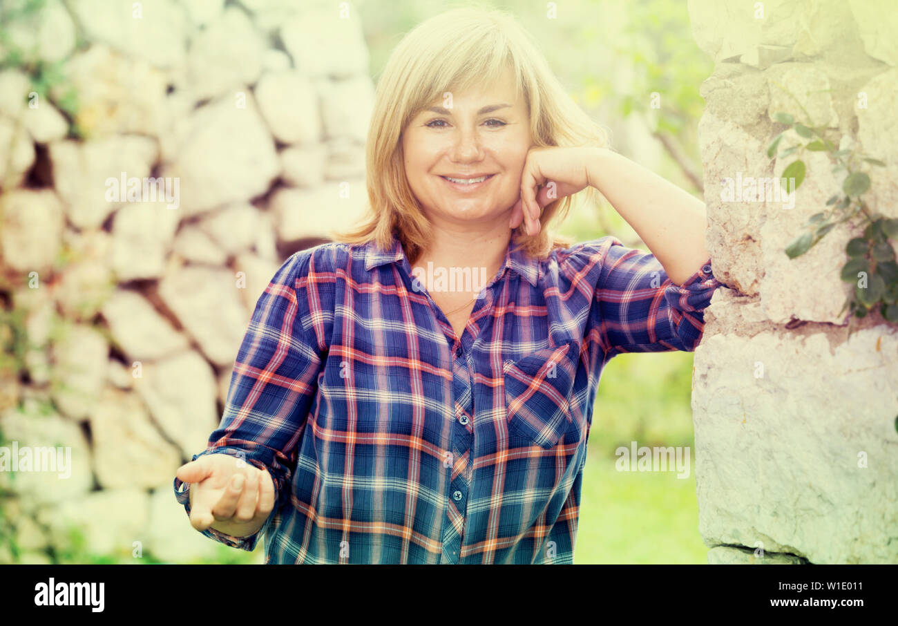 Portrait Of Cheerful Mature Woman Standing Outdoors In Garden Stock