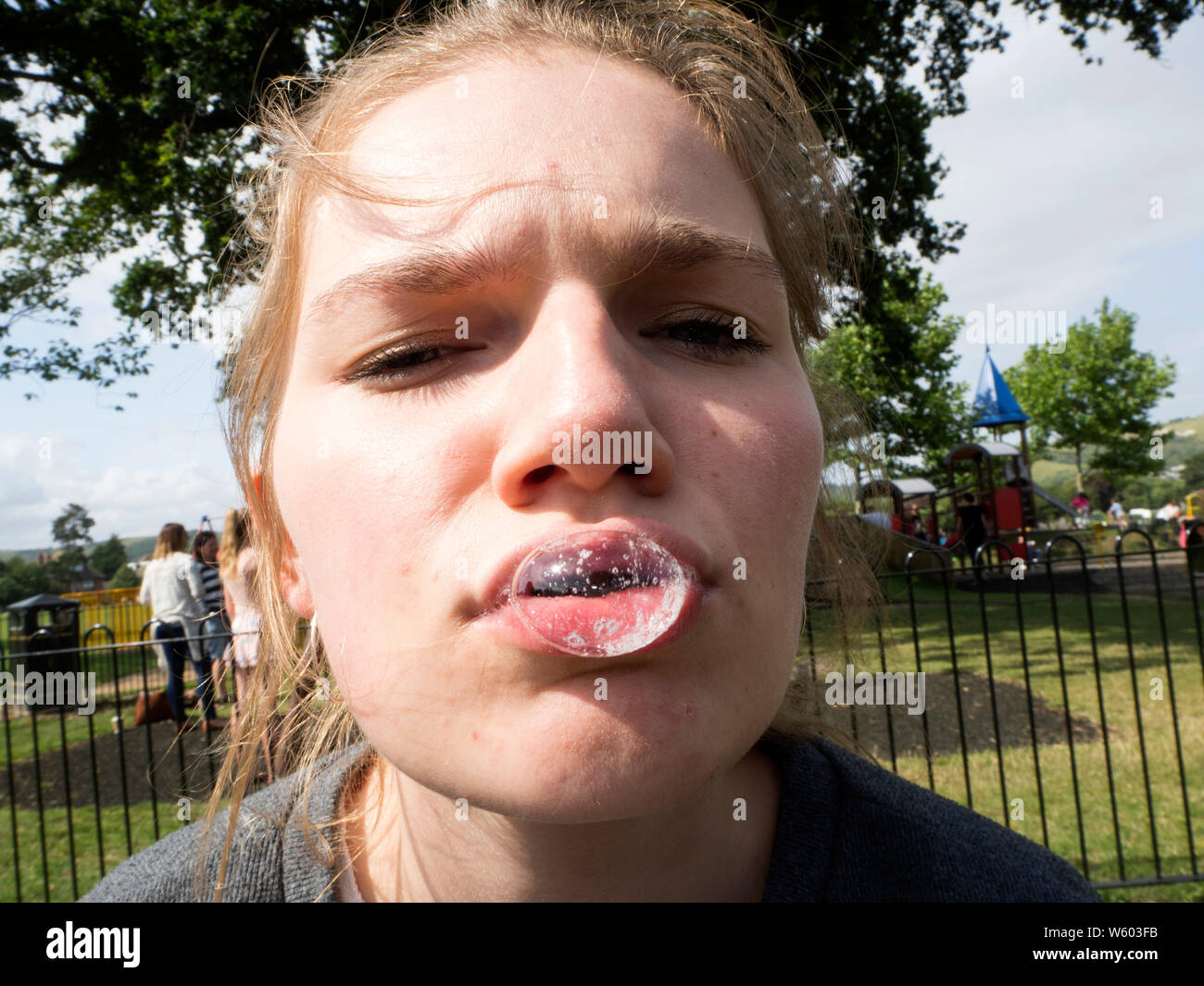 Teenage Girl Blowing Bubble From Her Mouth With Her Spit Stock Photo