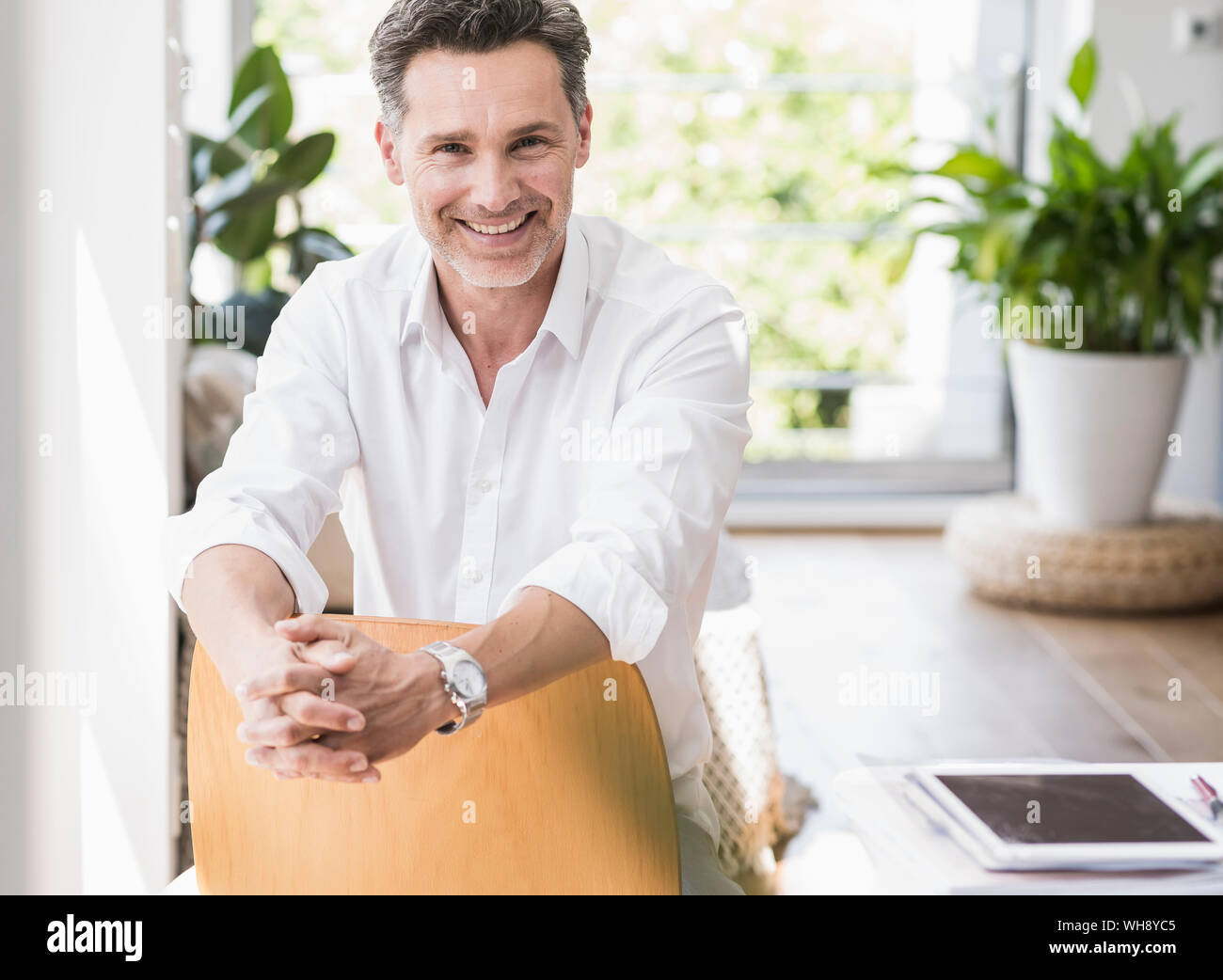 Mature Man Sitting On Chair Backwards Smiling Stock Photo Alamy