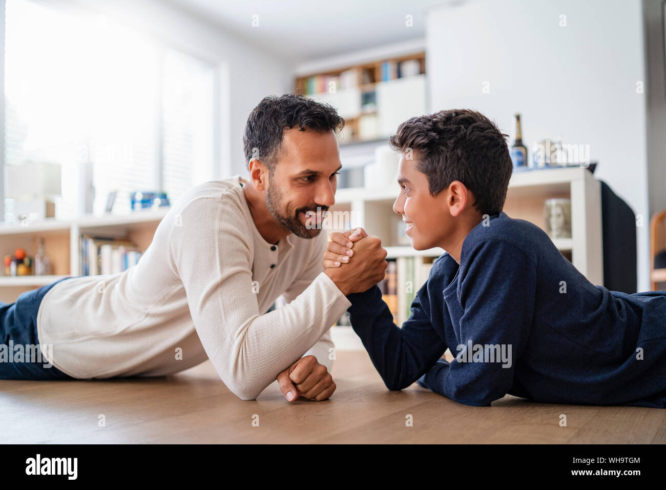 Father And Son Lying On The Floor At Home Arm Wrestling Stock Photo Alamy