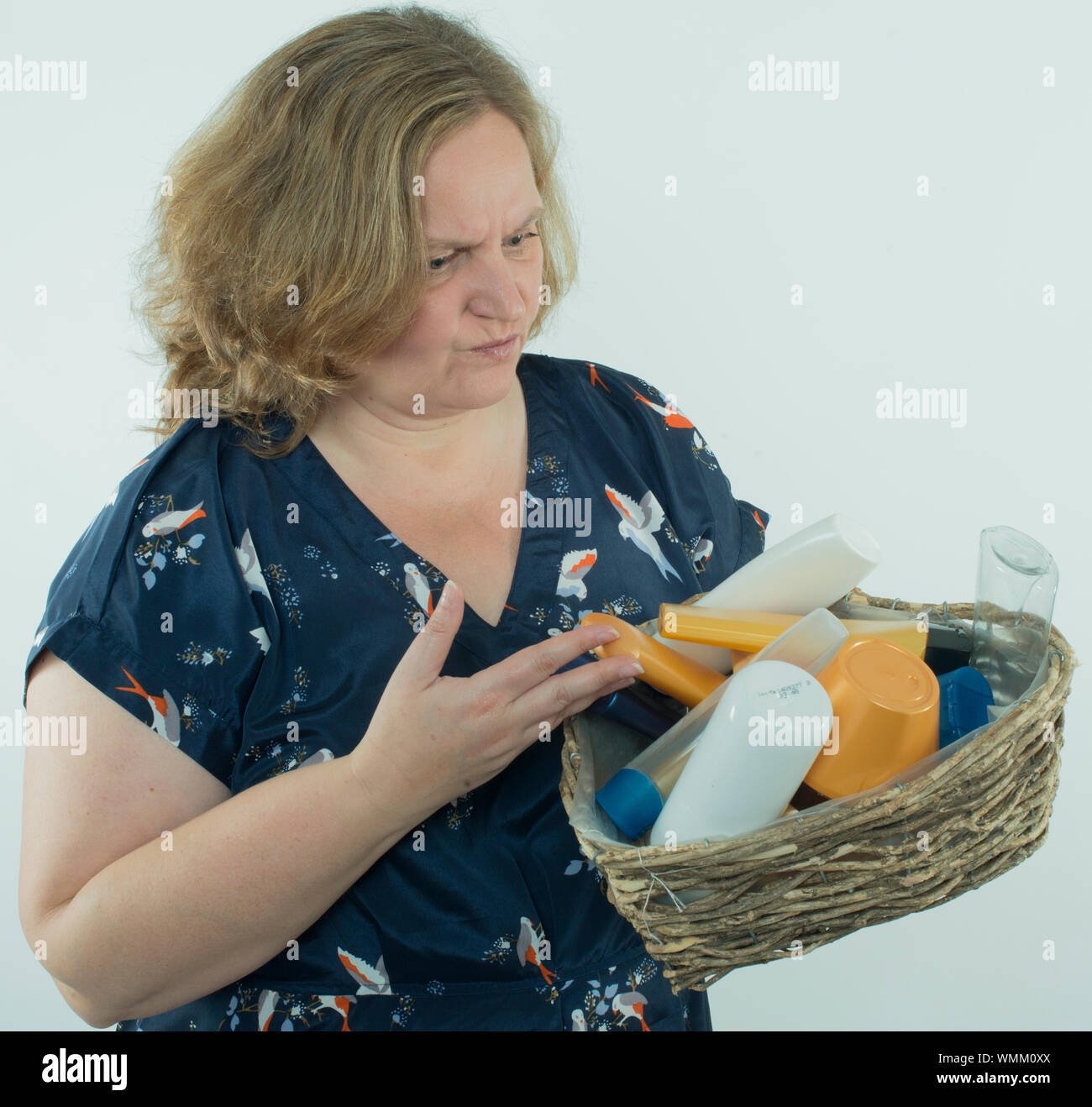 Mature Woman Holding Wicker Basket With Bottles Against White