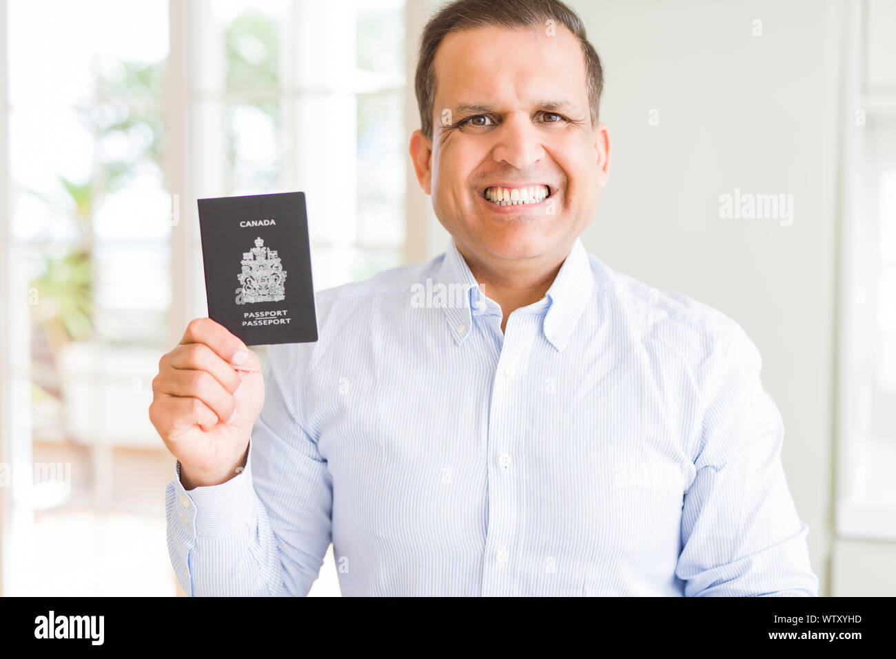 Middle Age Man Holding Holding Canadian Passport With A Happy Face