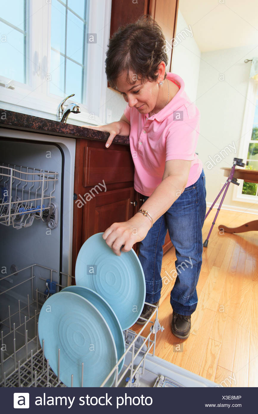 Woman With Cerebral Palsy Putting Dishes In A Dishwasher Woman With Cerebral Palsy Putting Dishes In A Dishwasher