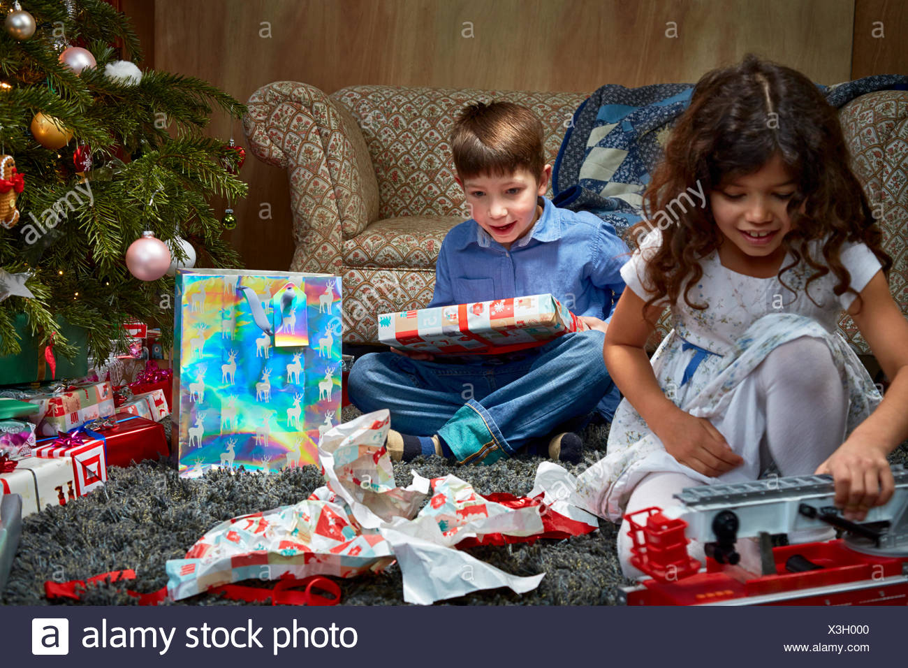 sister and brother in sitting room unwrapping and playing with christmas gifts - Brother Christmas Gifts sister and brother in sitting room unwrapping and playing with christmas gifts - Brother Christmas Gifts