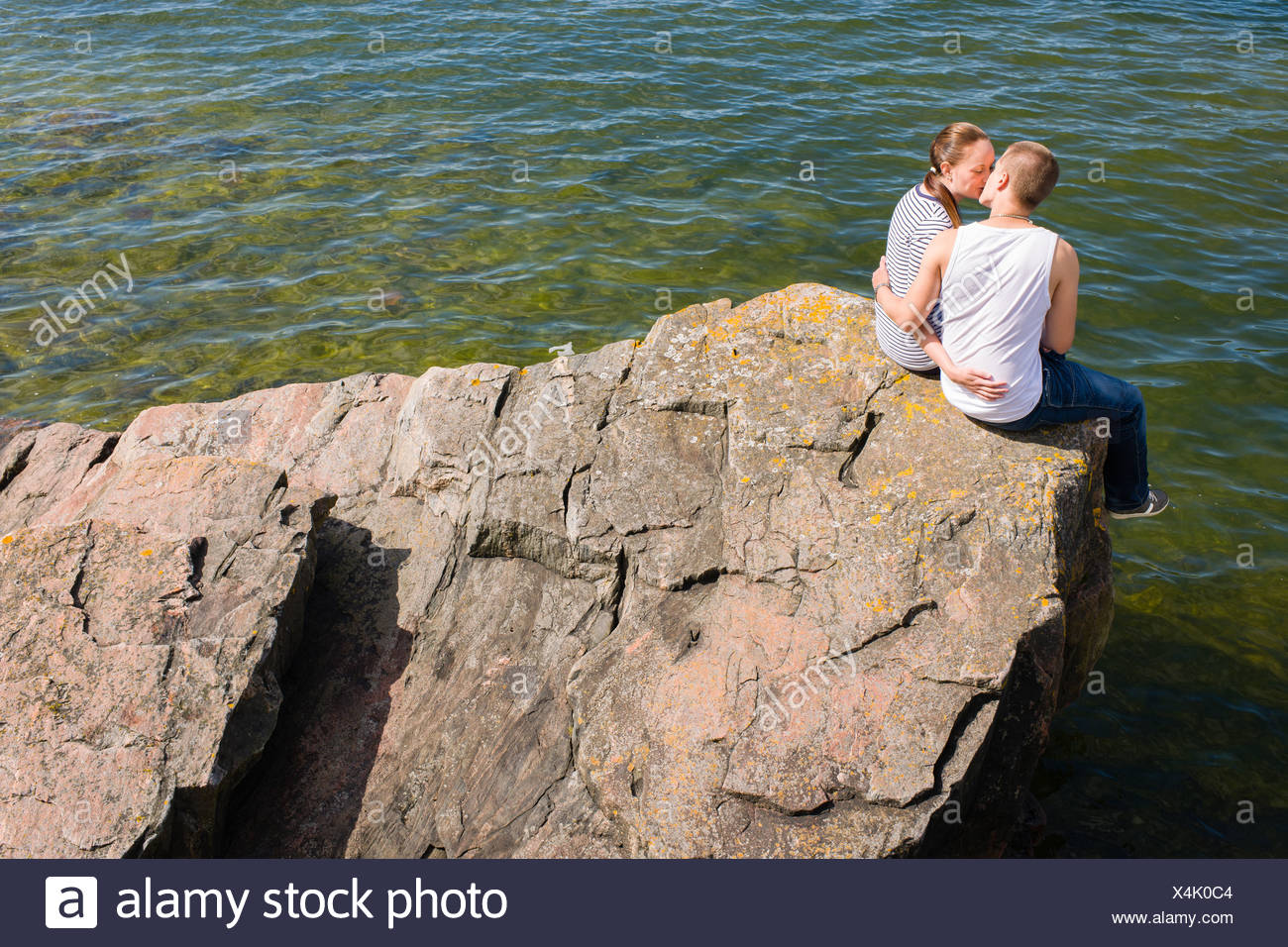 Young Lovers Sitting And Kissing On The Big Rock Young Lovers Sitting And Kissing On The Big Rock