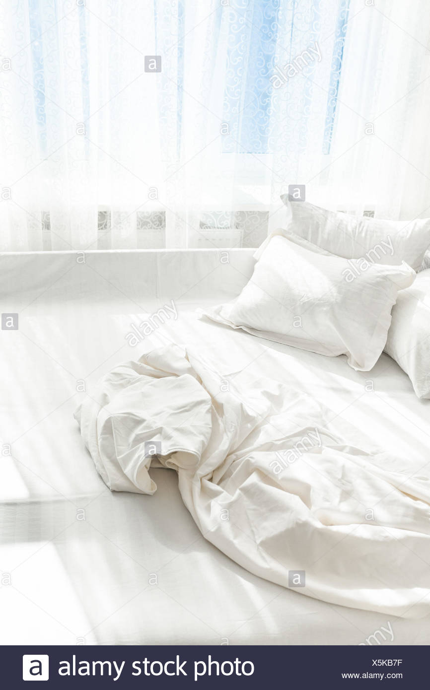 Photo of unmade bed against window