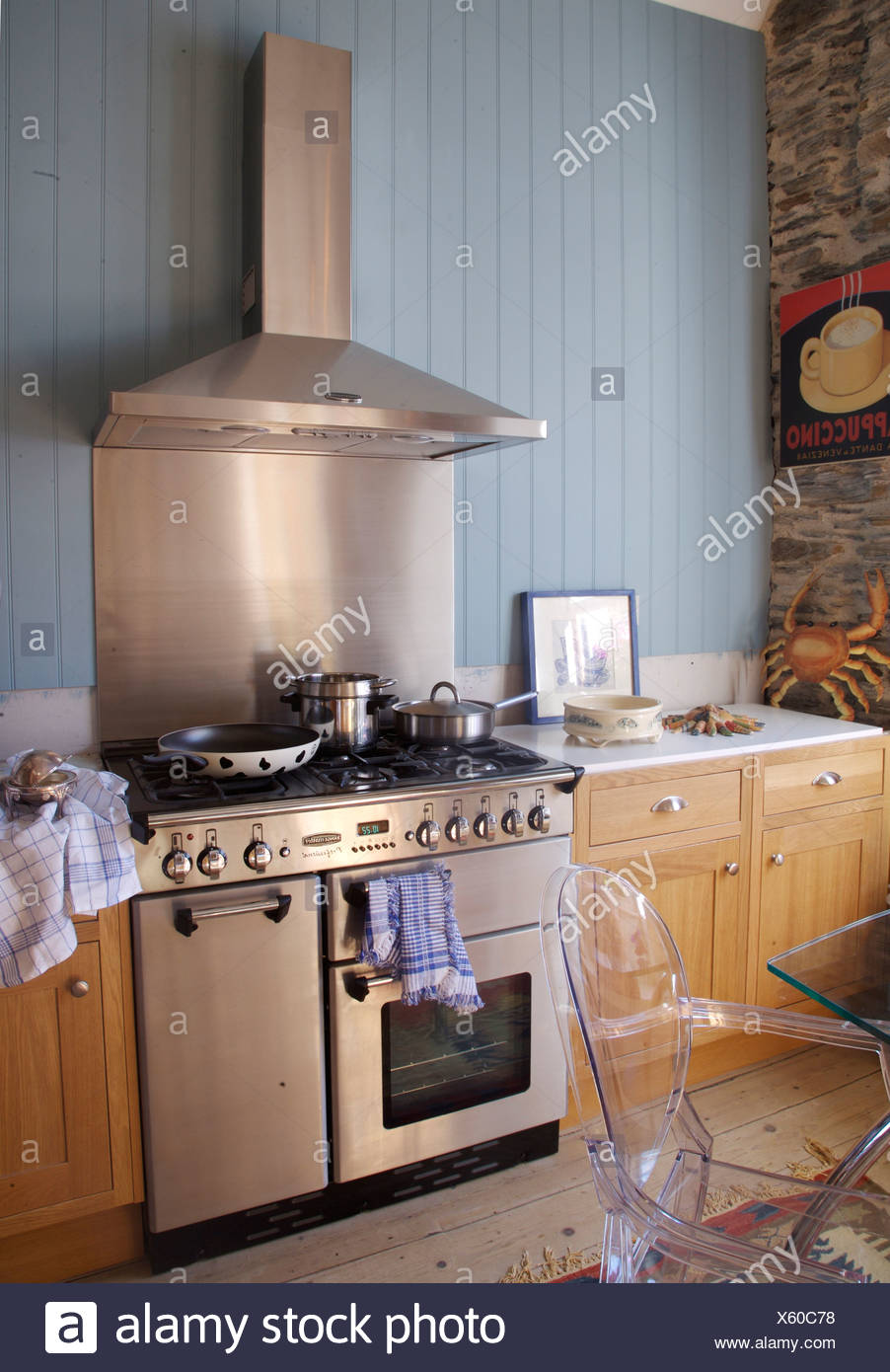 Stainless steel splash back cooker hood above range oven and cooker hood in country kitchen with blue tongue groove paneling