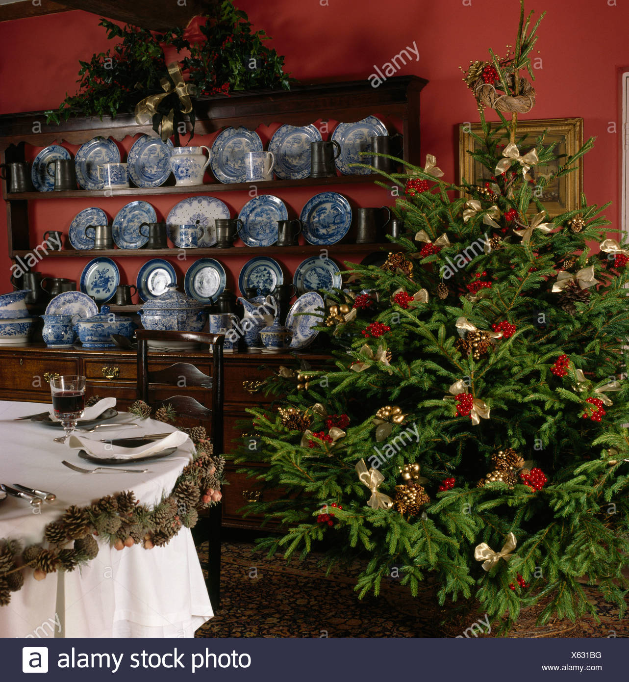 Christmas Tree Beside Antique Dresser With Collection Of Blue White China In Red Dining Room Decorated For Christmas Tree Beside Antique Dresser With Collection Of Blue White China In Red Dining Room Decorated For