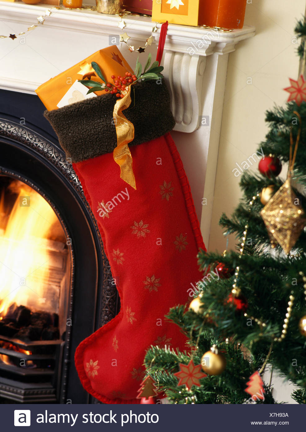 Close Up Of Red Felt Christmas Stocking Hanging On Mantelpiece Beside Small Artificial Tree Close Up Of Red Felt Christmas Stocking Hanging On Mantelpiece Beside Small Artificial Tree