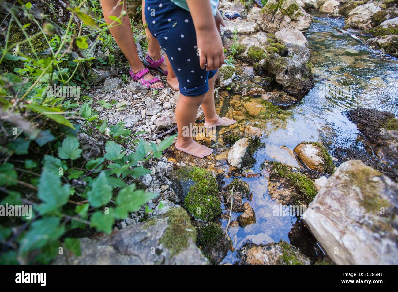 Kinder barfuß Fuß zu Fuß durch klares Wasser in Wald Bach Abenteuer am