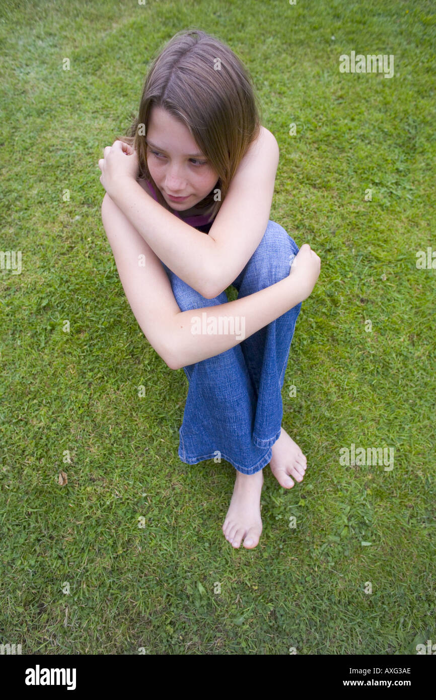 UK CORNWALL 12 13 JÄHRIGE MÄDCHEN SITZEN AUF RASEN RASEN PARK GARTEN