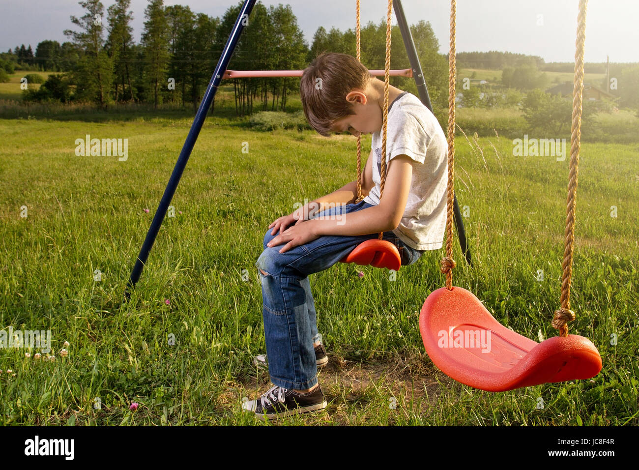 Traurig einsam Junge sitzt auf Schaukel allein Stockfoto, Bild
