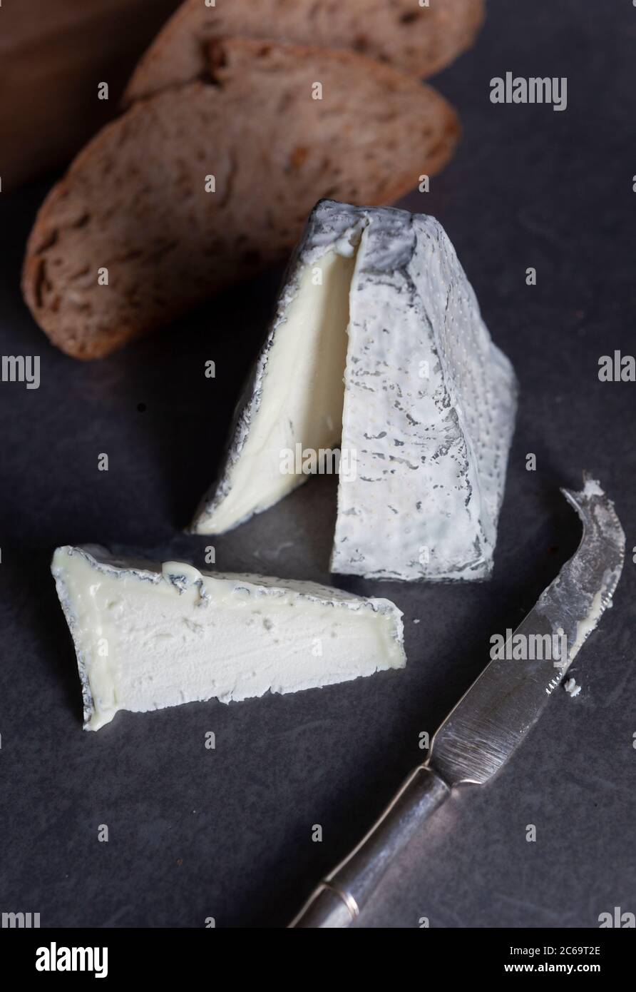 Una pirámide de queso de cabra cubierto de ceniza con pan tostado de