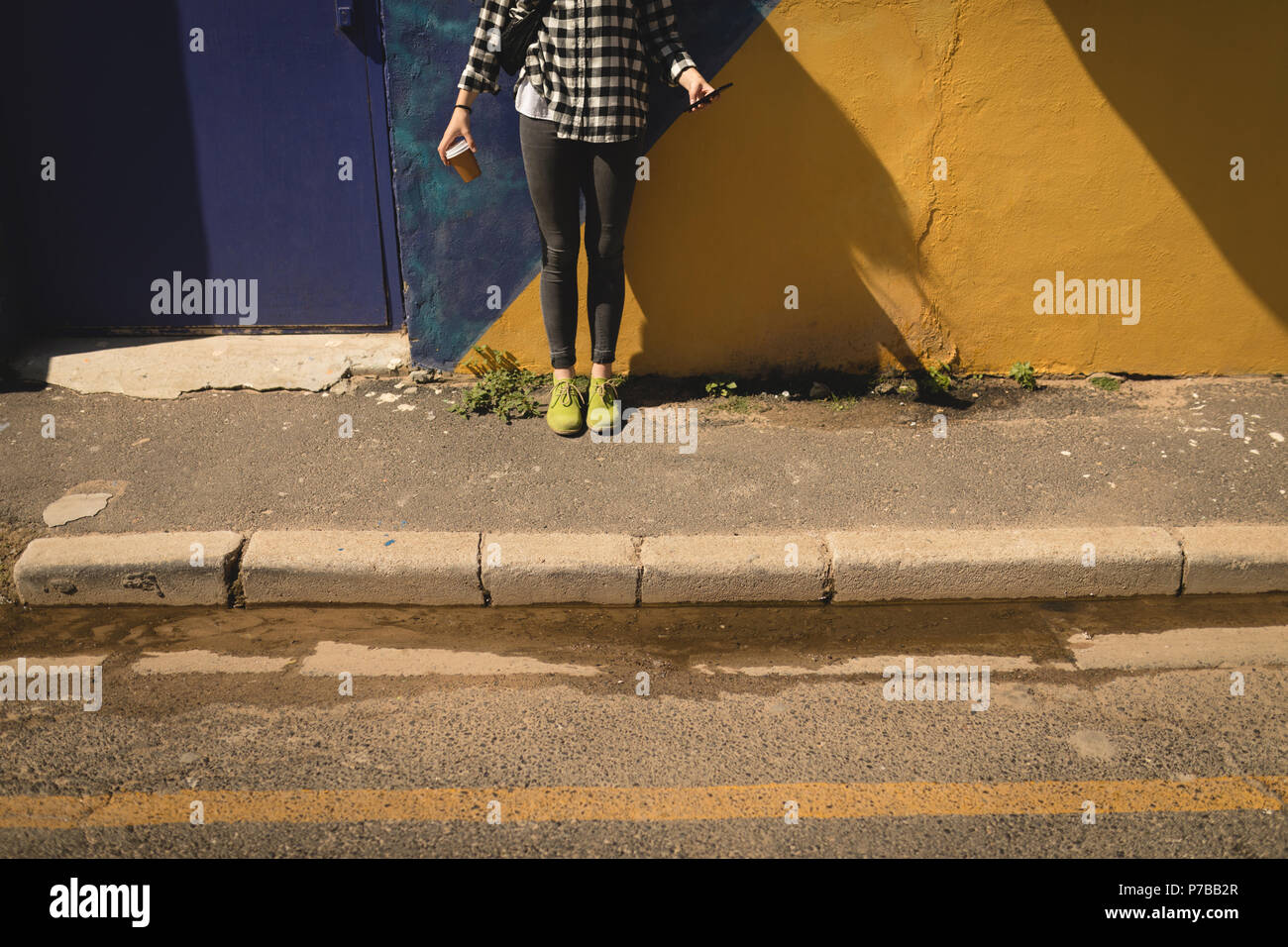Une femme debout contre un mur Banque de photographies et dimages à