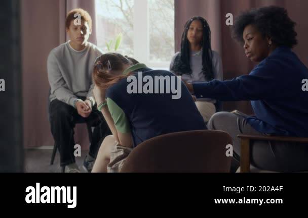 Back view shot of depressed teen girl surrounded by diverse peers and ...