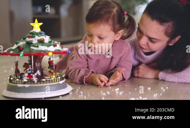 Pretty Mother And Cute Little Child Girl Looking At Christmas Musical 