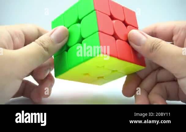 A hand spinning a 3x3 Rubik's cube that is not scrambled on a white ...