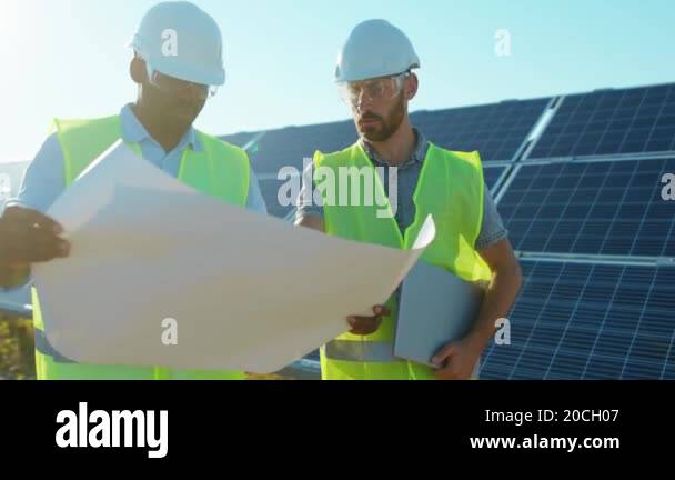 At sunlight two engineers with project plan on the solar farm in ...