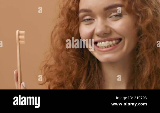 A young woman with curly red hair smiles brightly while holding a ...
