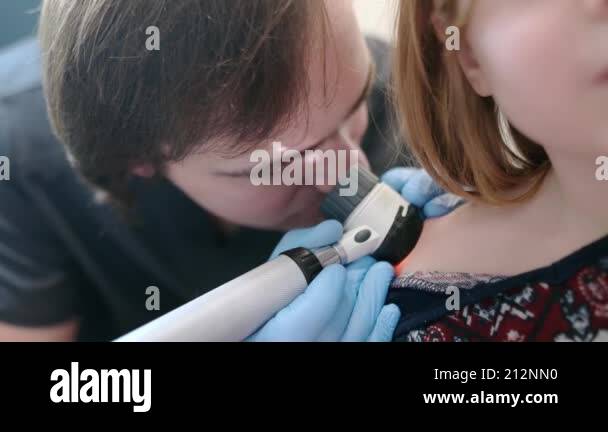 A caring doctor checks moles on the skin of a small child. A ...