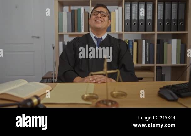 Young hispanic man in a judge's robe sitting in an office with legal ...
