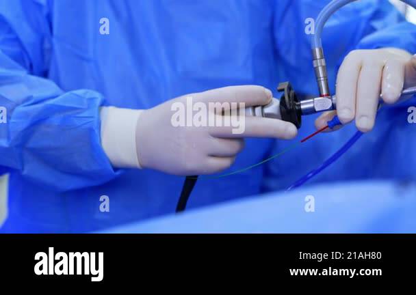 Gloved hands of a doctor holding a modern surgical device. Endoscopic ...