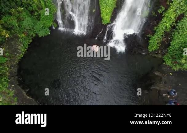 A couple of people are standing under a beautiful green waterfall ...