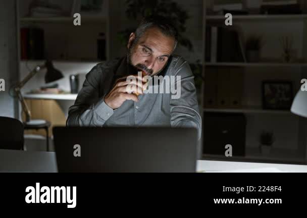 Bearded Mature Man Works Late On Laptop In Dark Home Office While 