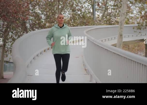 Active woman jogging in a park bridge, showcasing determination and ...