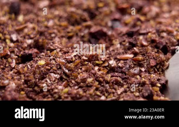 Scooping a baking cocoa toppings with flax seeds and dried black ...