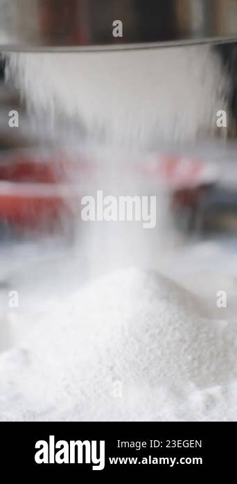 Vertical close up view of flour being sifted through metal sieve on ...
