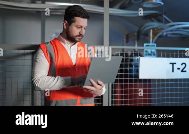 Professional electrical engineer with a beard types on a laptop in ...