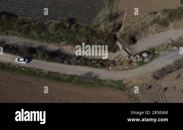 Aerial view of car driving on farmland and dirt road between valley ...