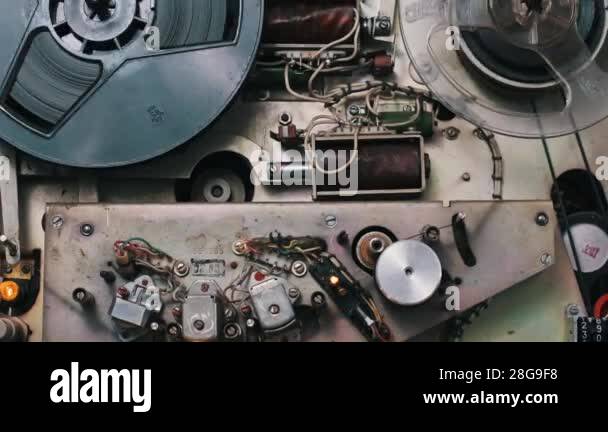 Close-up view of a vintage reel-to-reel tape recorder in operation. The ...