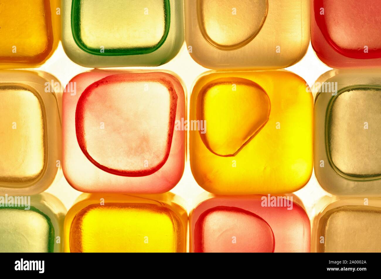 Plastic transparent colored ice cubes arranged in rows with harsh LED back lights resulting in a colorful abstract background. Stock Photo